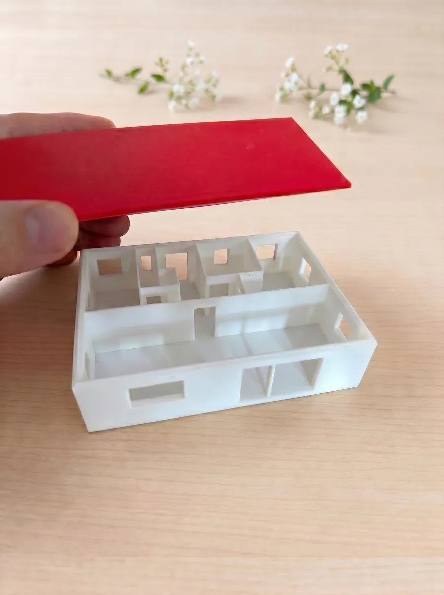 Hand lifting the red roof piece off the model